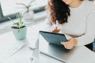 a woman sitting at a desk writing on a tablet