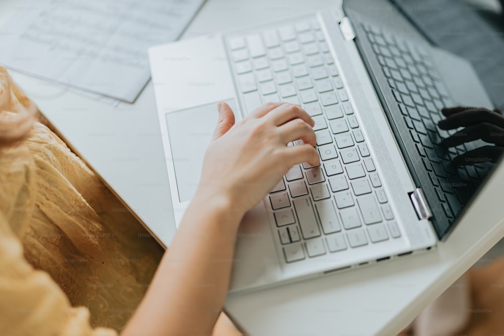 a person typing on a laptop computer on a desk