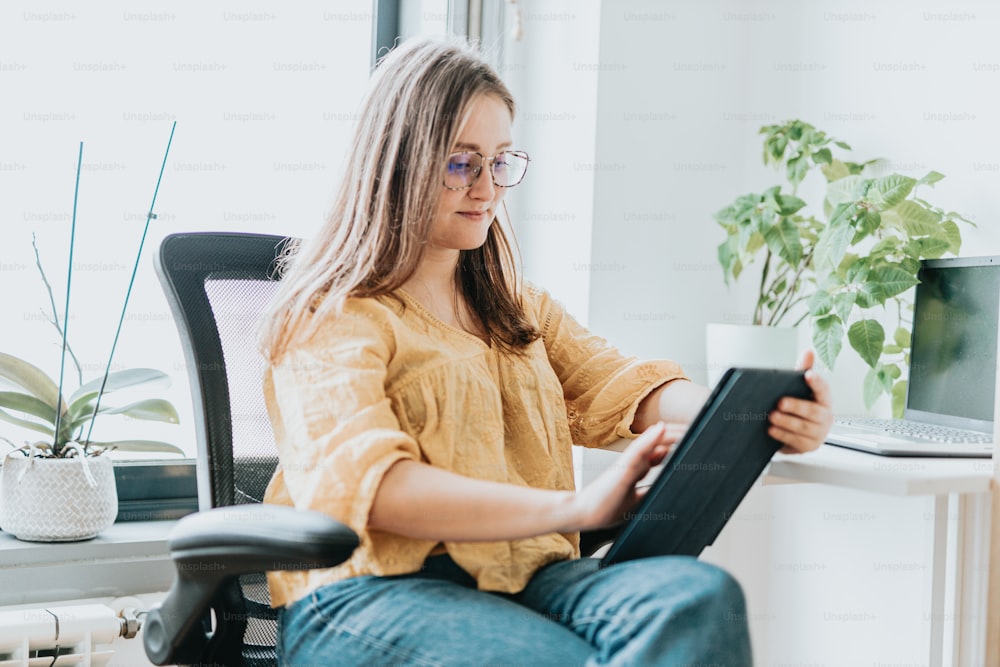 a woman sitting in a chair holding a tablet