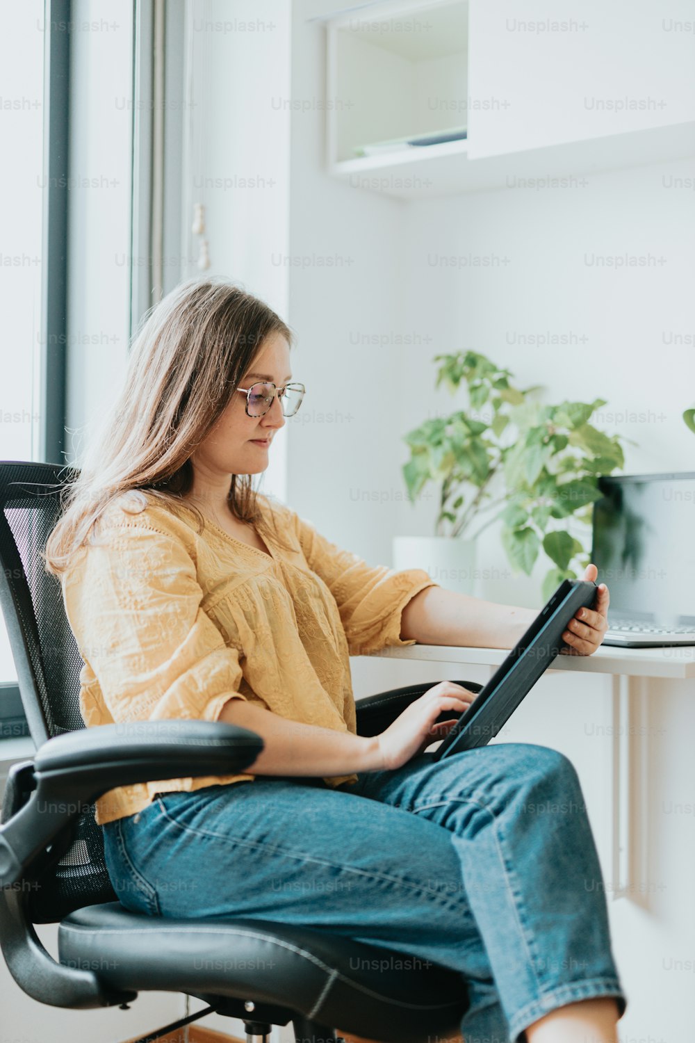 uma mulher sentada em uma cadeira usando um computador portátil