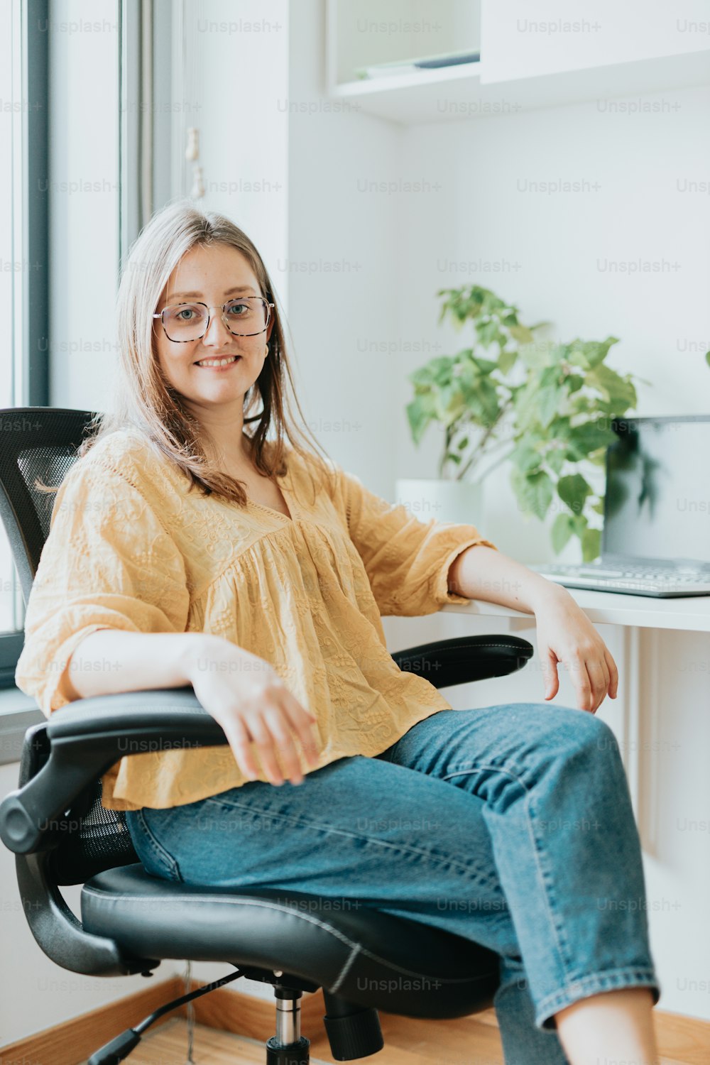 Eine Frau sitzt mit gekreuzten Beinen auf einem Bürostuhl