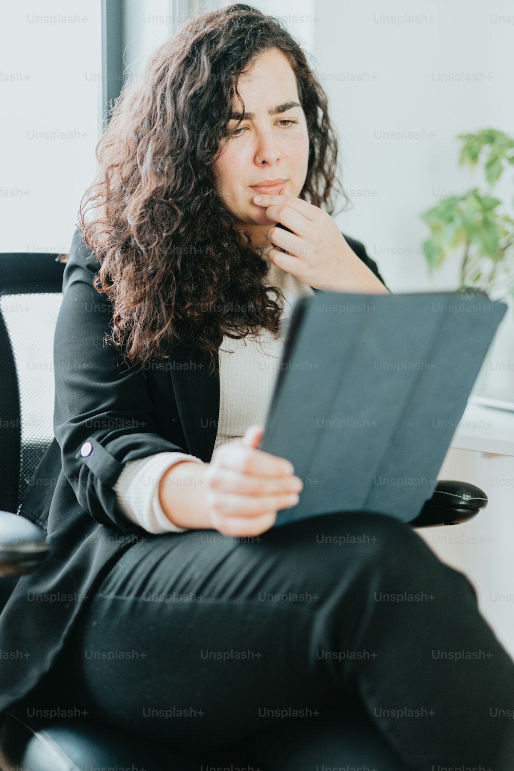 Eine Frau sitzt auf einem Stuhl und hält ein Tablet in der Hand
