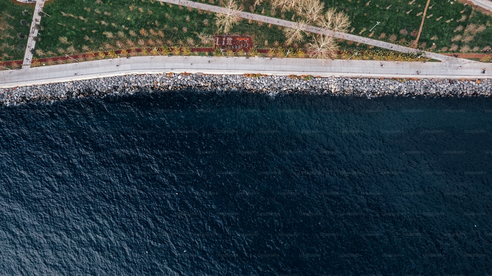 an aerial view of a road next to a body of water