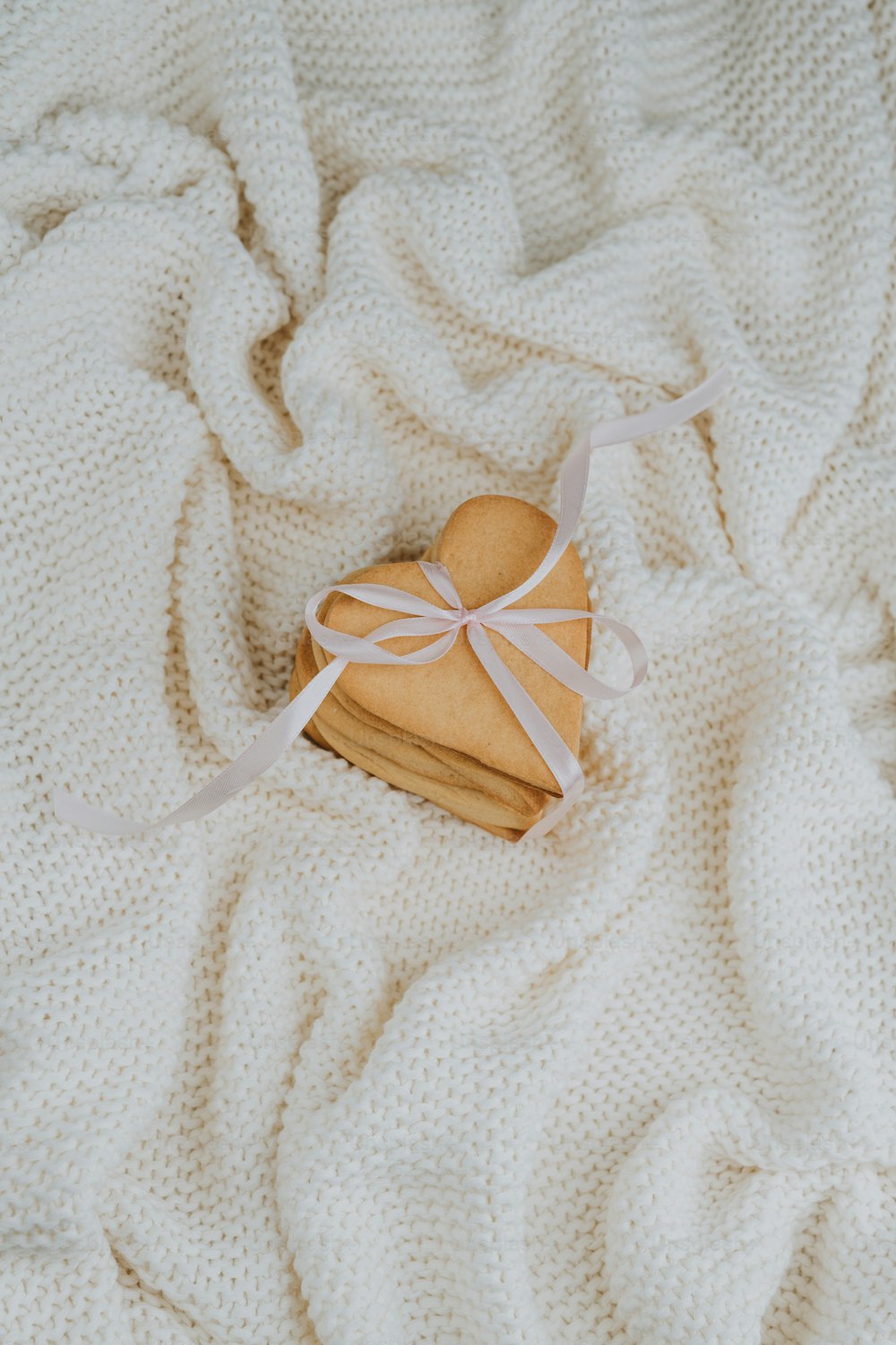 a heart shaped cookie on a white blanket