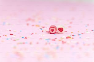 un paio di tappi per le orecchie rosa a forma di cuore circondati da sprinkles