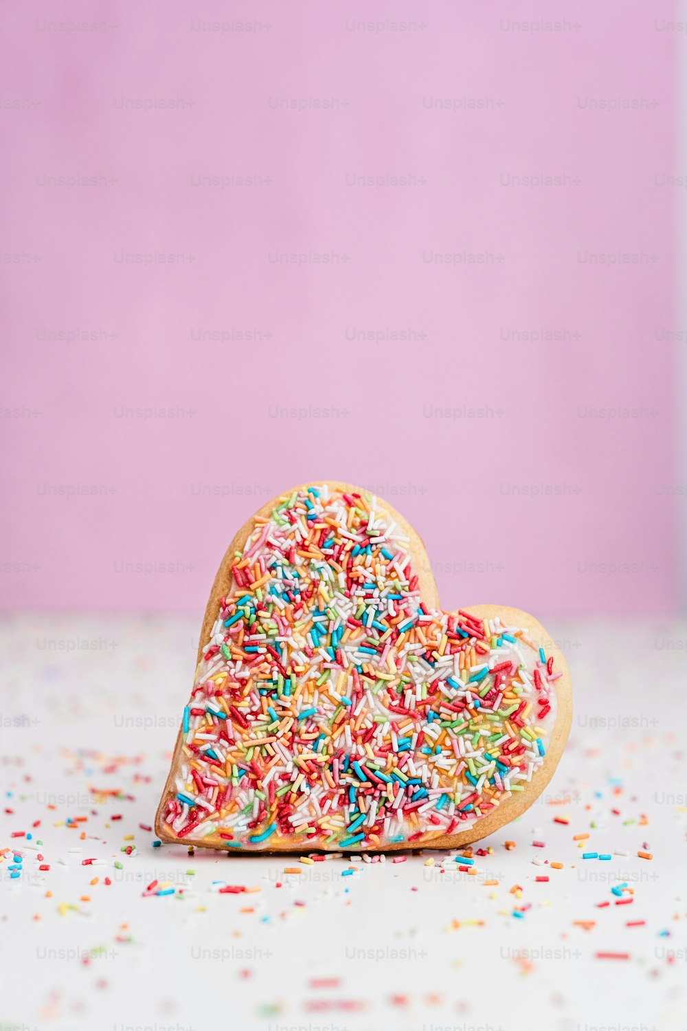 a heart shaped cookie with sprinkles on a table