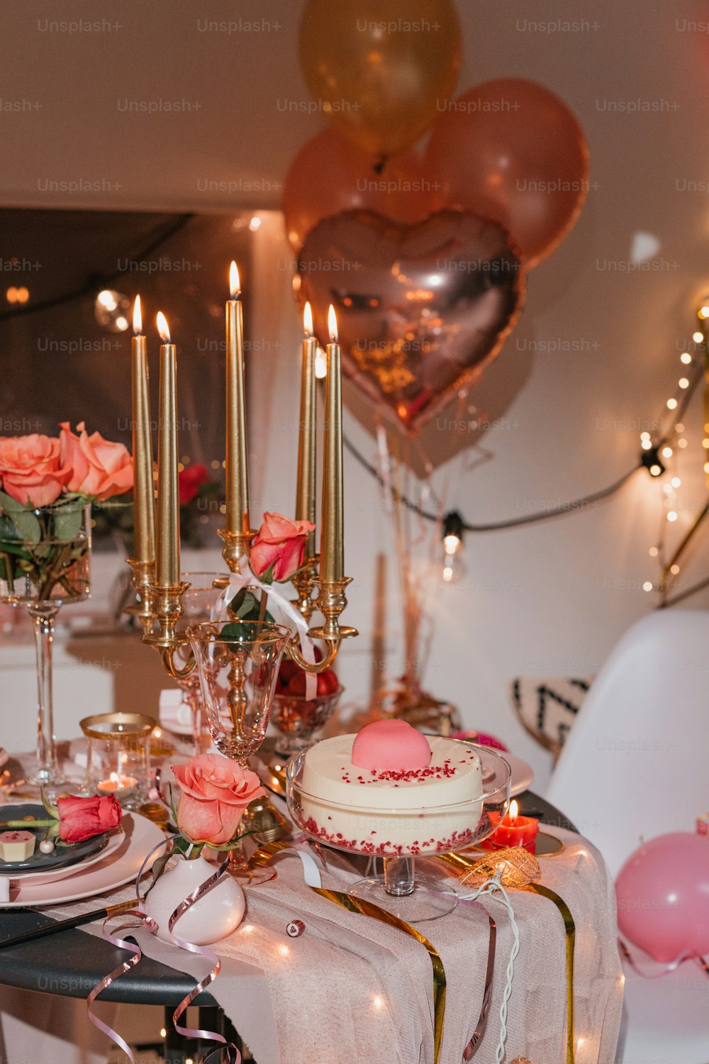 a table topped with a cake and lots of balloons