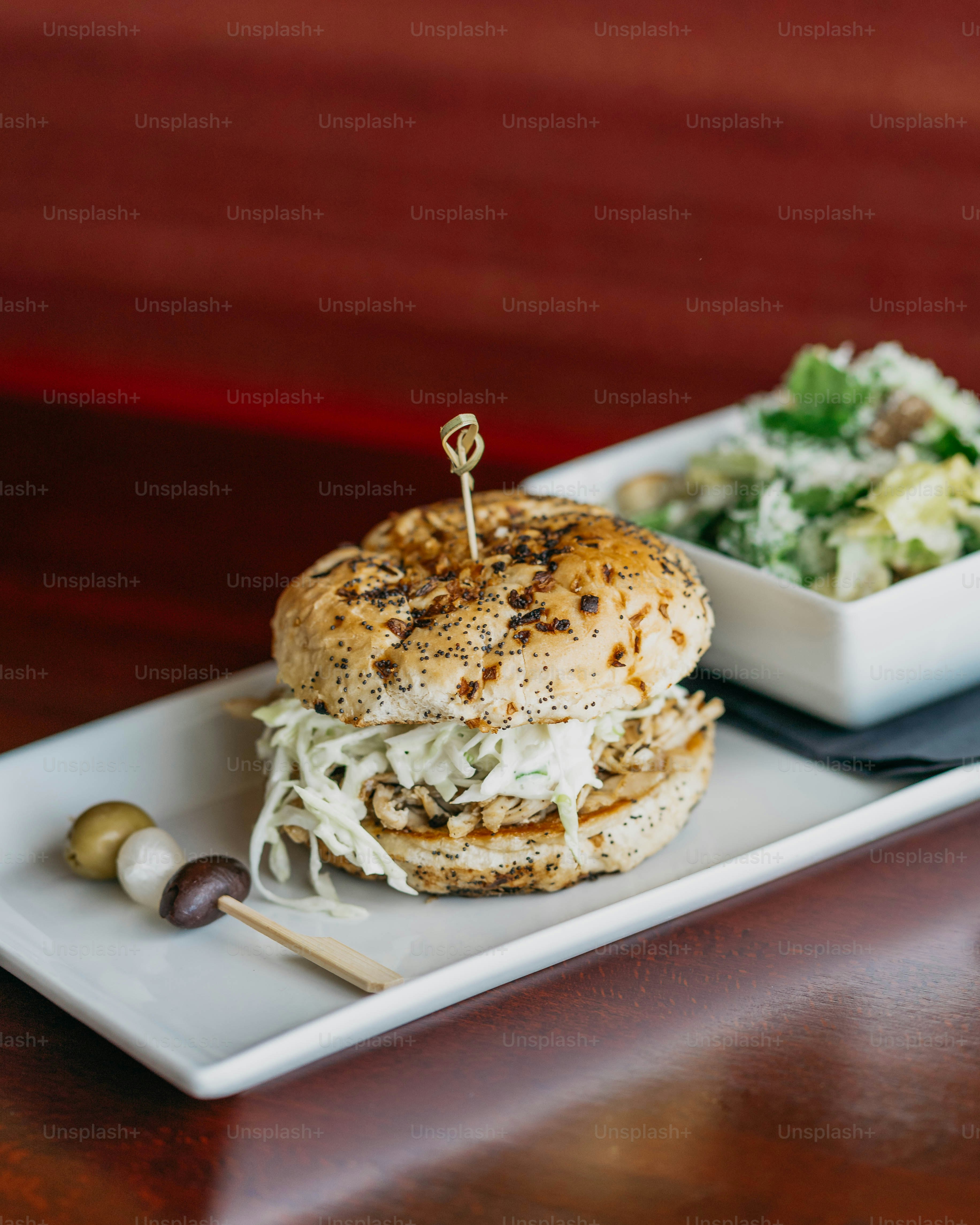a white plate topped with a sandwich next to a bowl of salad