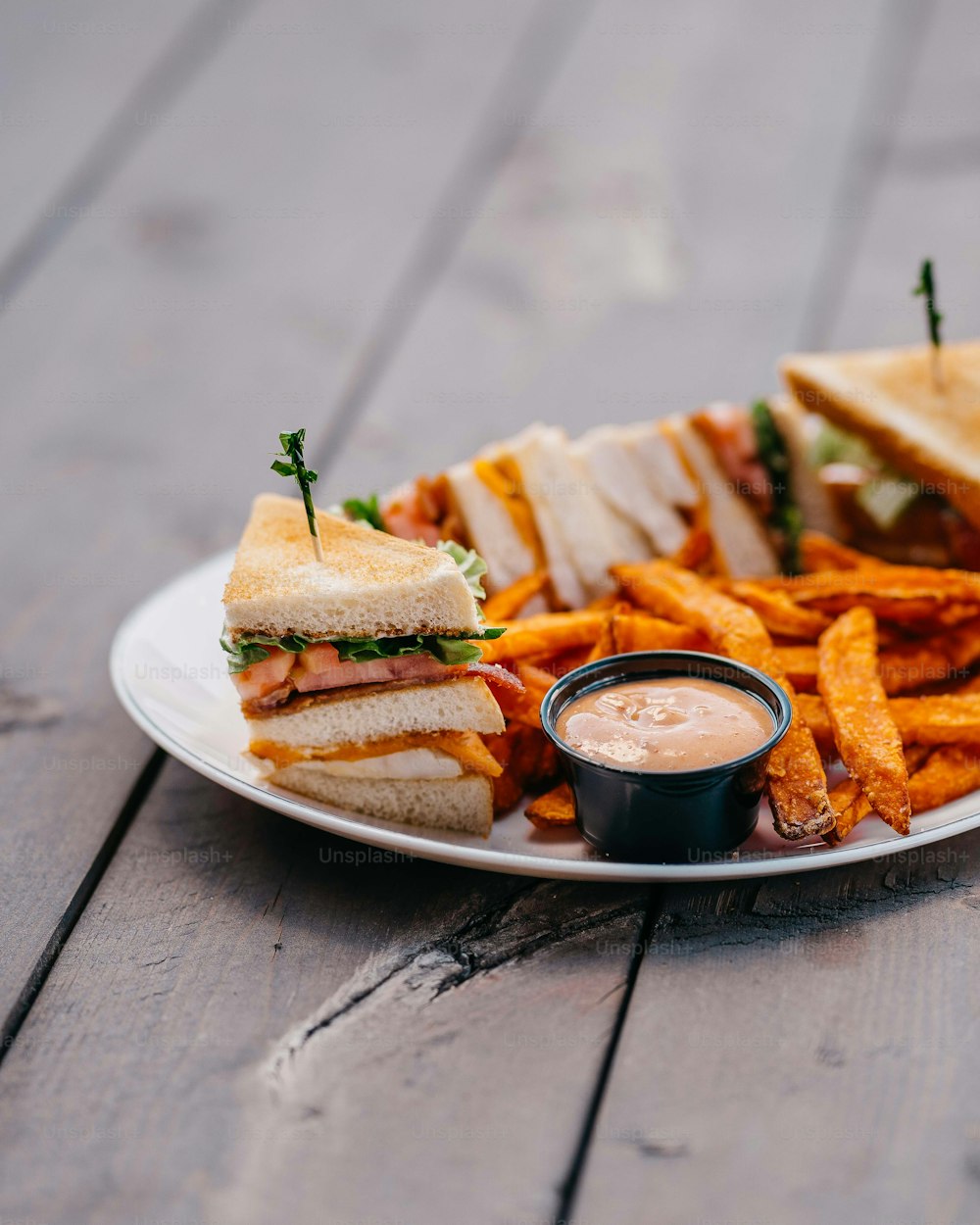 a white plate topped with a cut in half sandwich and fries