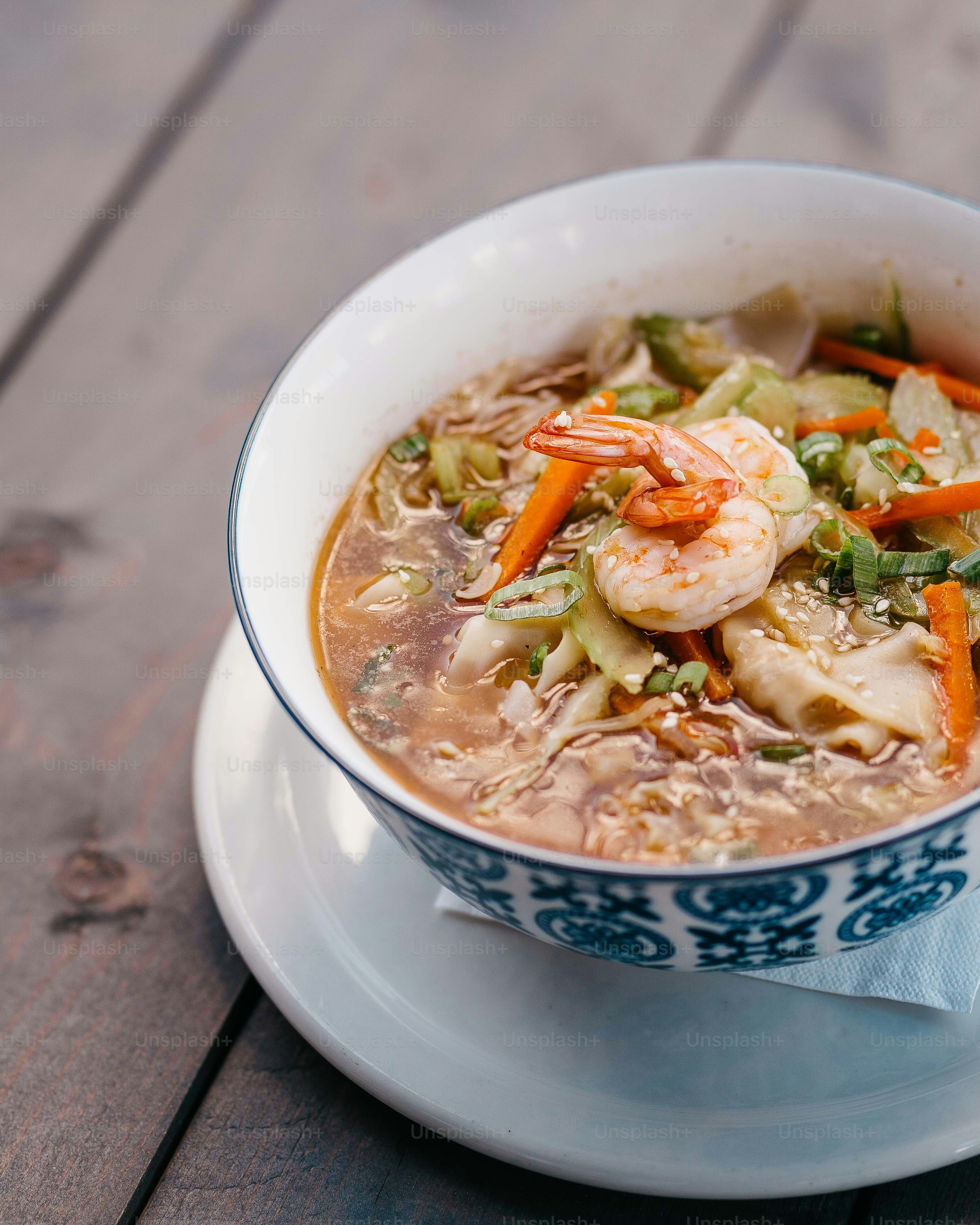 a bowl of soup with shrimp and carrots