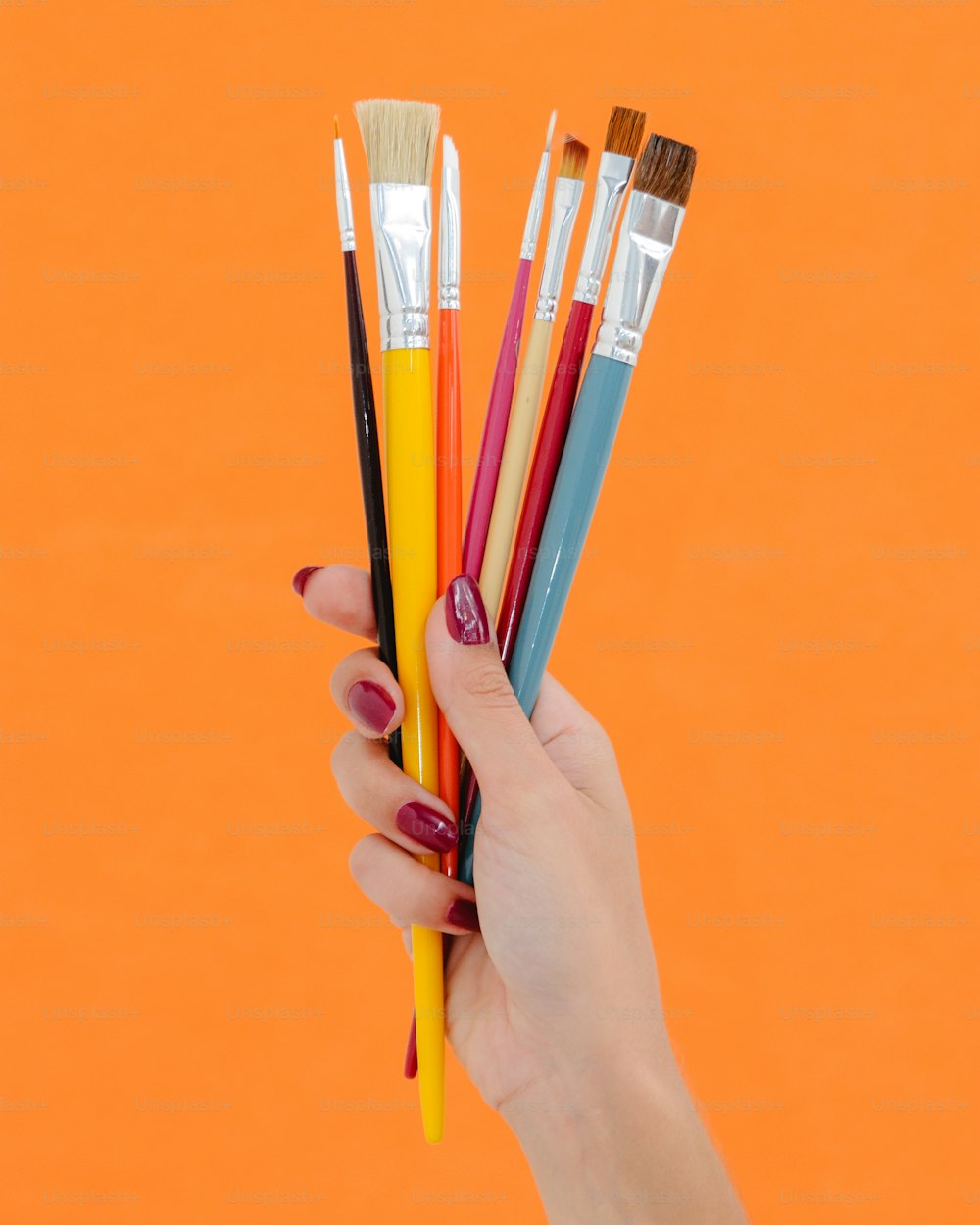 a hand holding a bunch of paint brushes