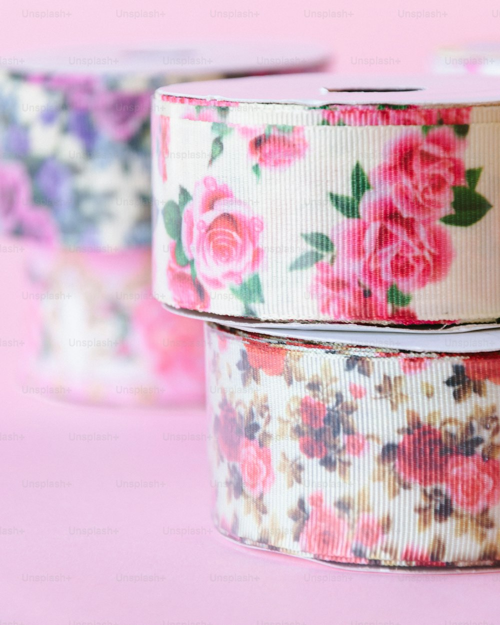 two rolls of floral ribbon on a pink background