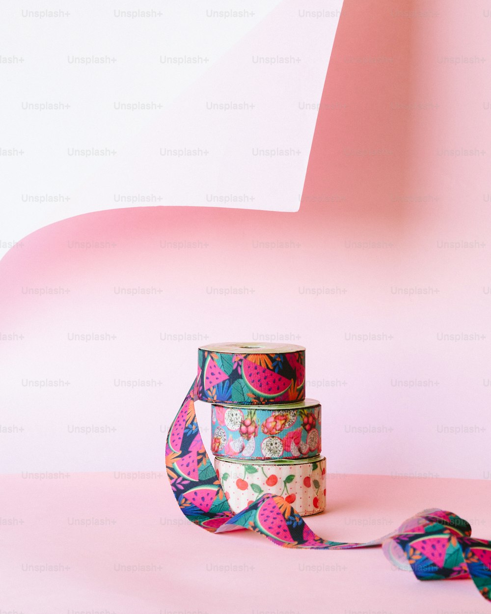 Un rollo de cinta de colores sentado encima de una superficie rosa