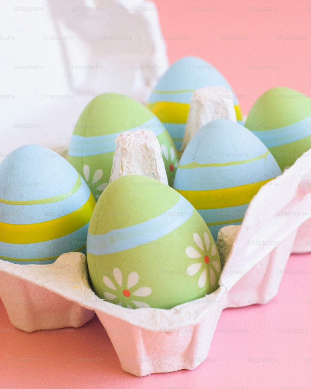 a carton filled with green and blue decorated eggs
