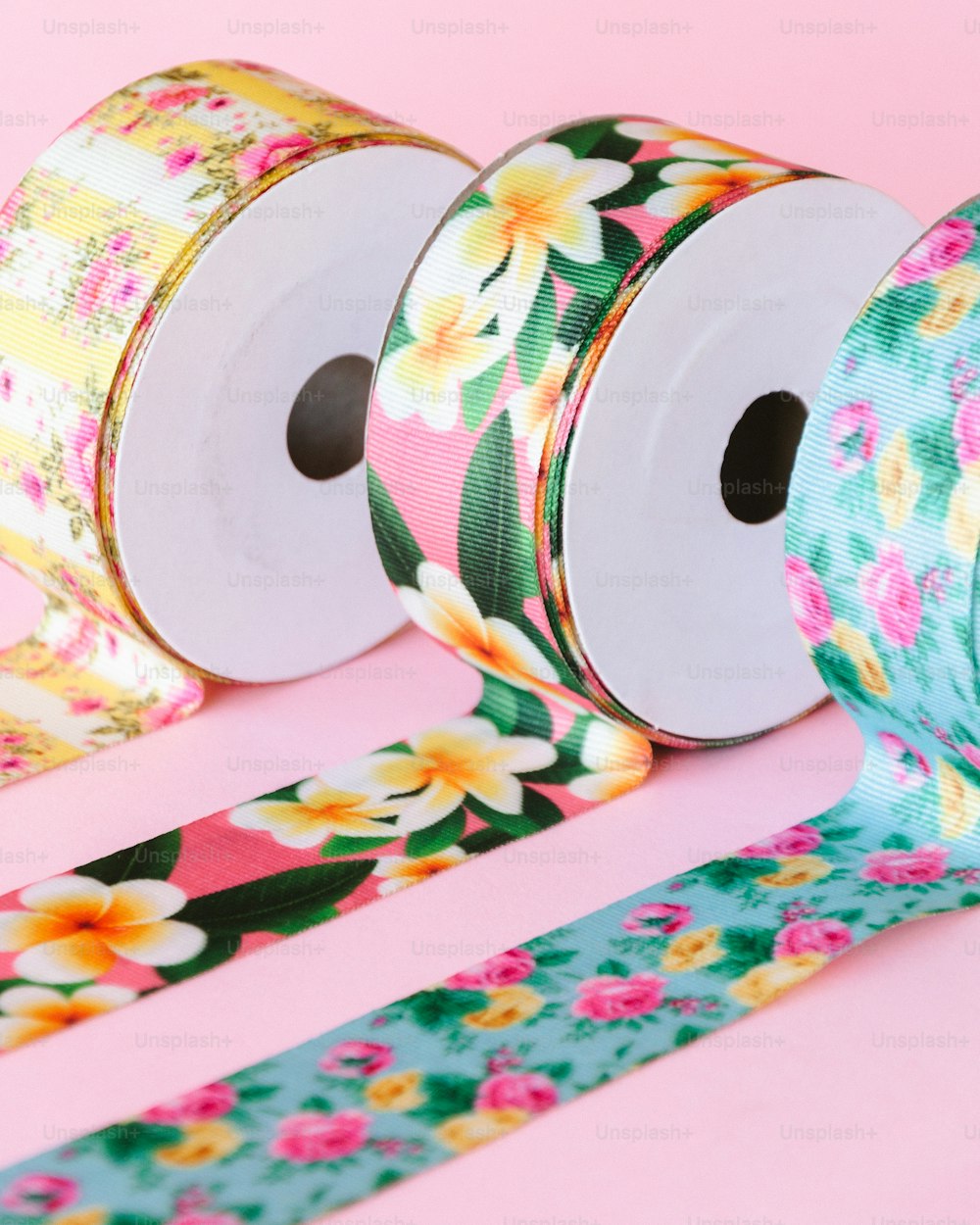 three rolls of floral washi tape on a pink background