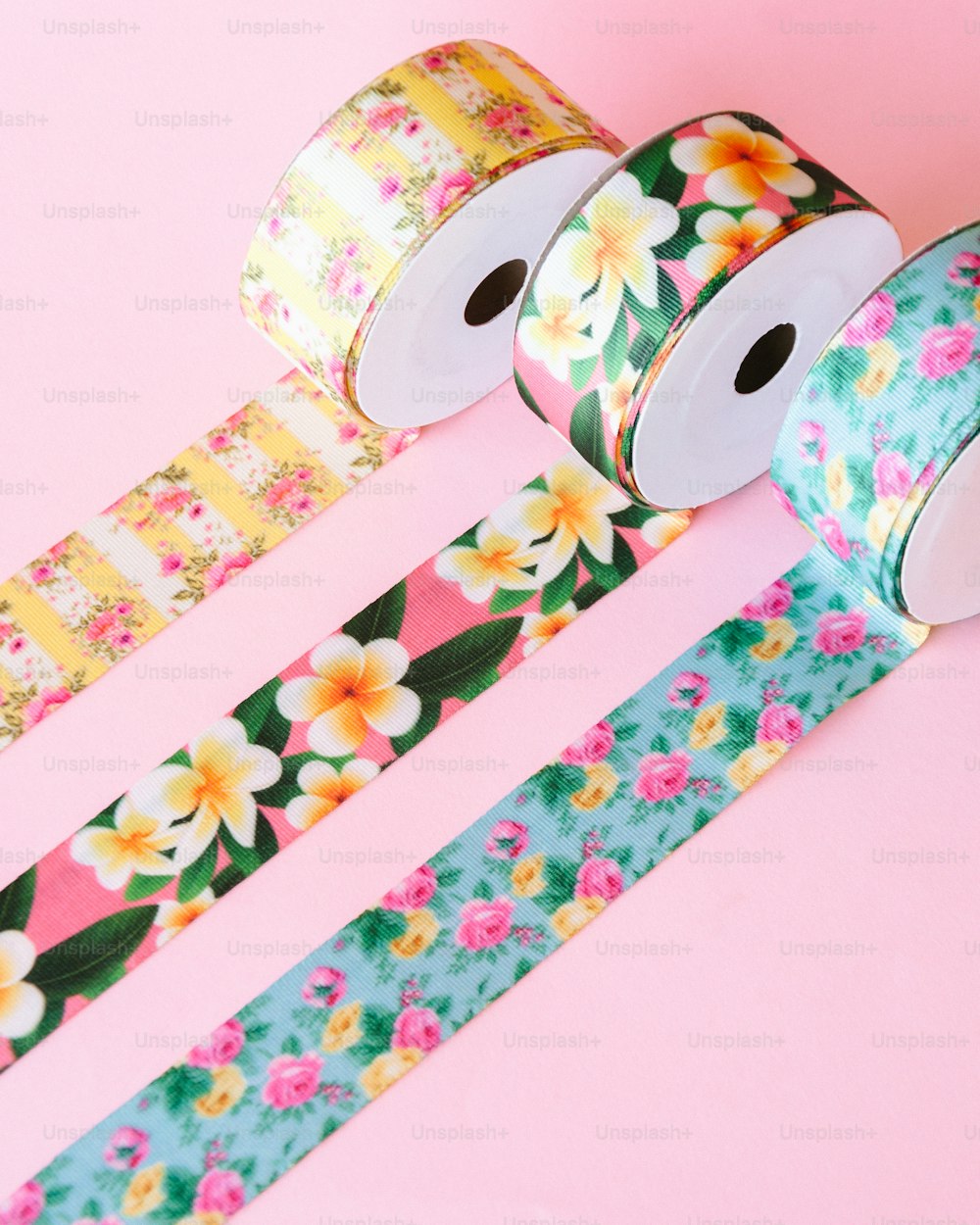 drei Rollen florales Washi-Tape auf rosa Hintergrund