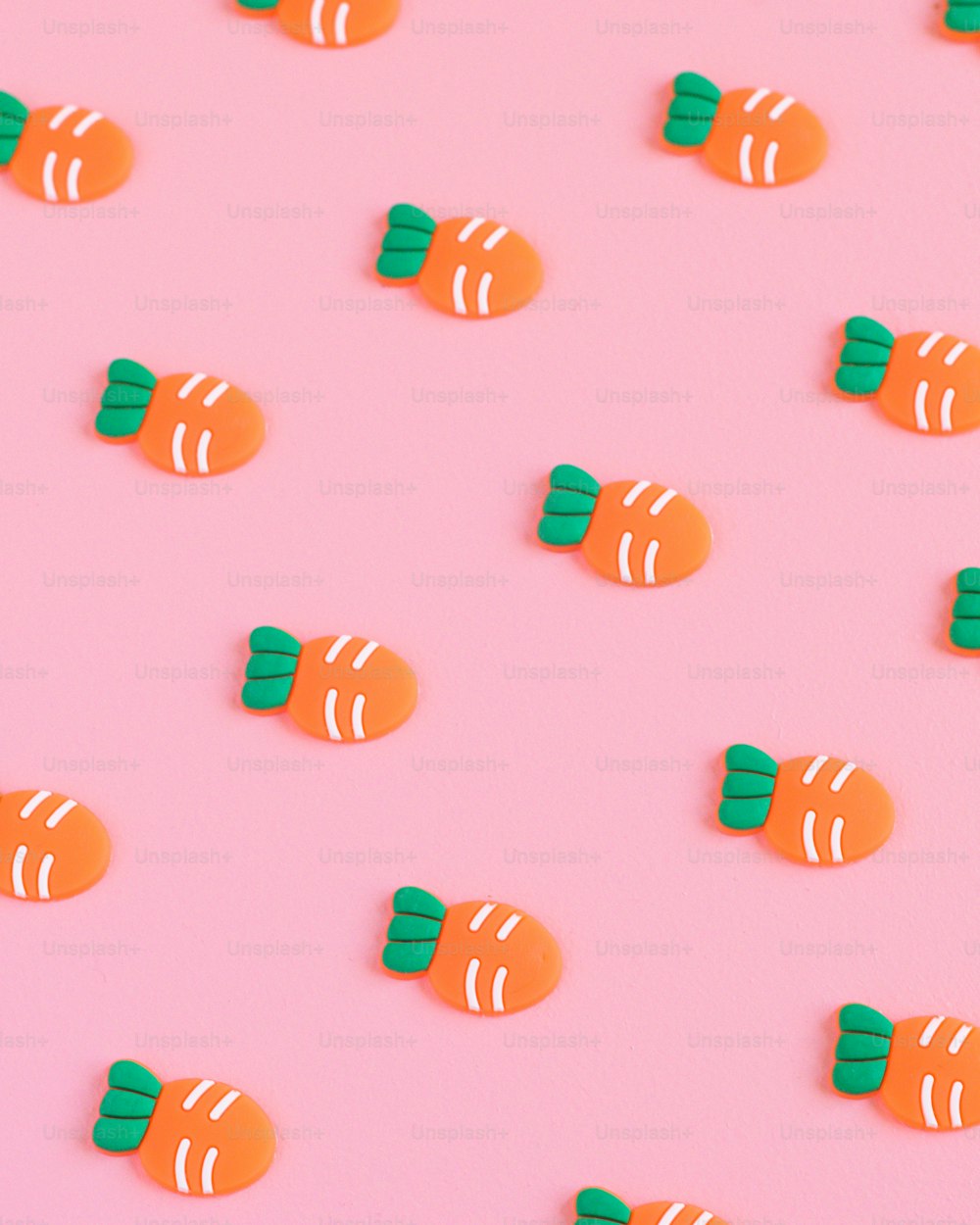 a group of orange and green candy candies on a pink background