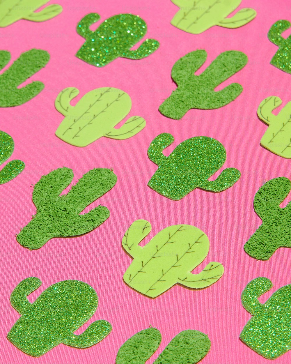 a pink background with green glittered cactus shapes