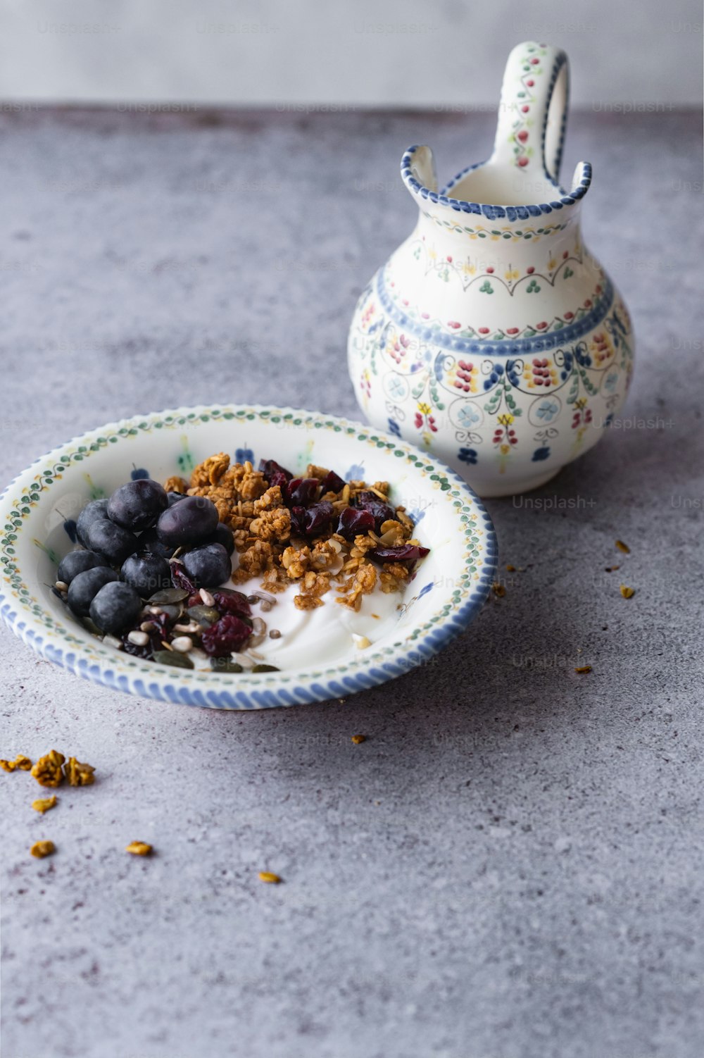 a bowl of granola and yogurt next to a vase