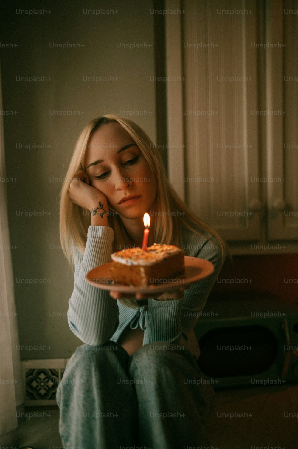 una donna che tiene una torta con una candela su di essa
