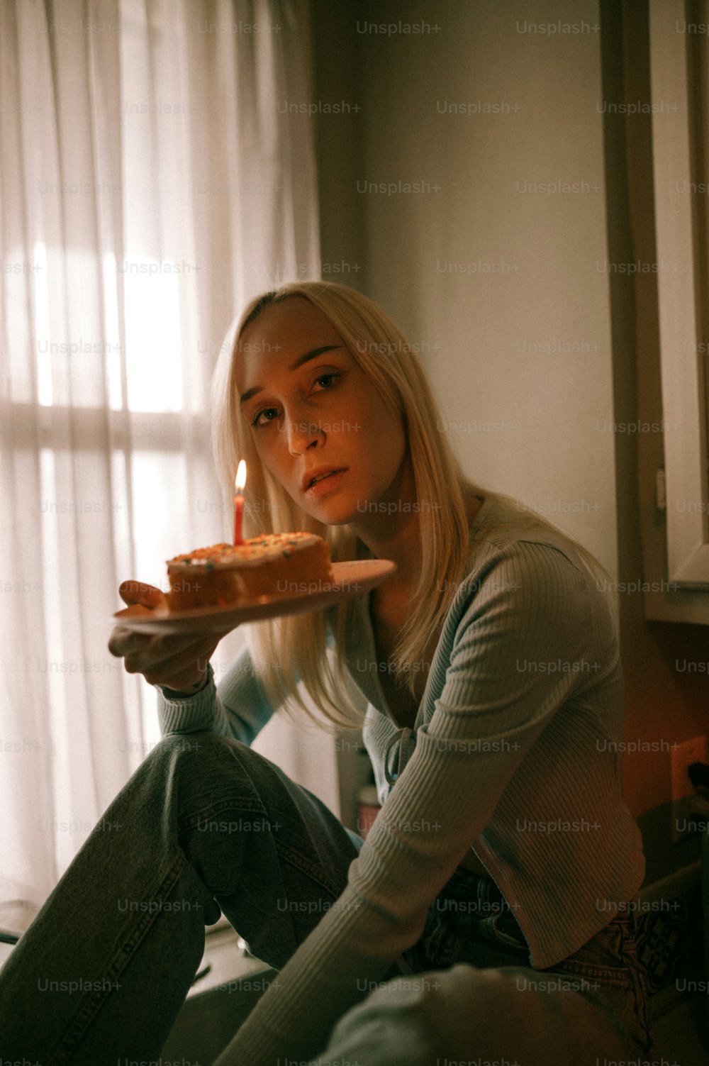 uma mulher sentada em uma cama segurando um pedaço de bolo