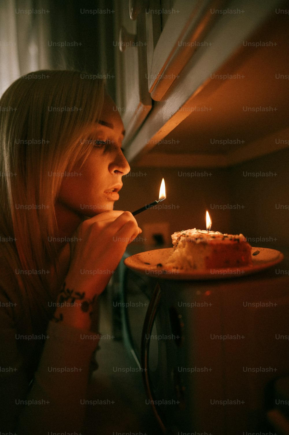 a woman looking at a cake with a lit candle on it