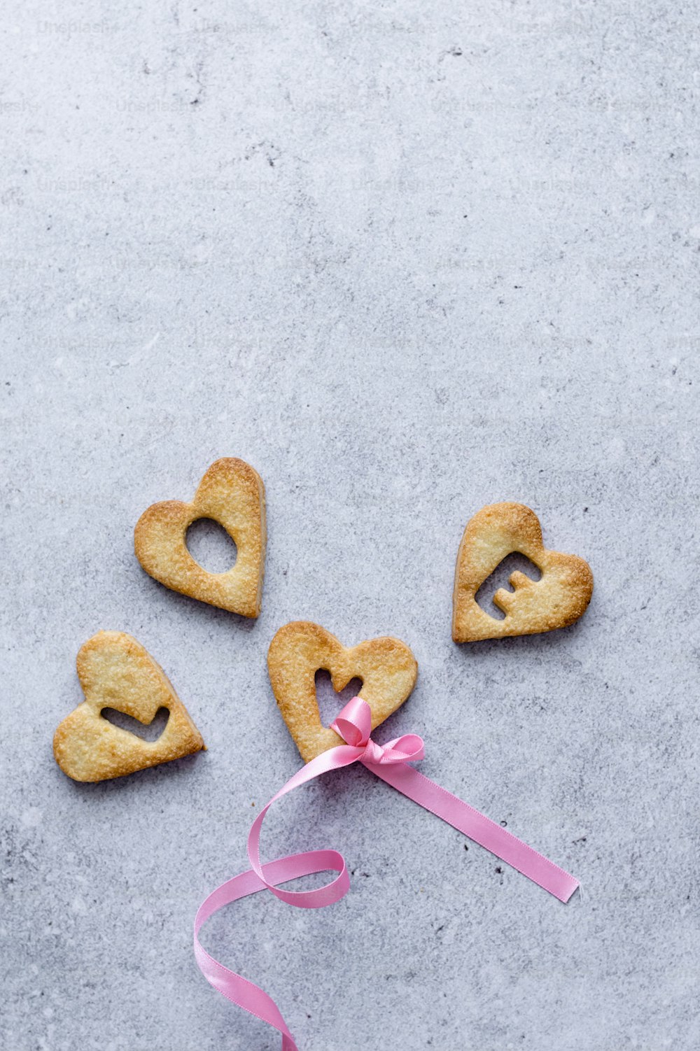 Trois biscuits en forme de cœur attachés à un ruban rose