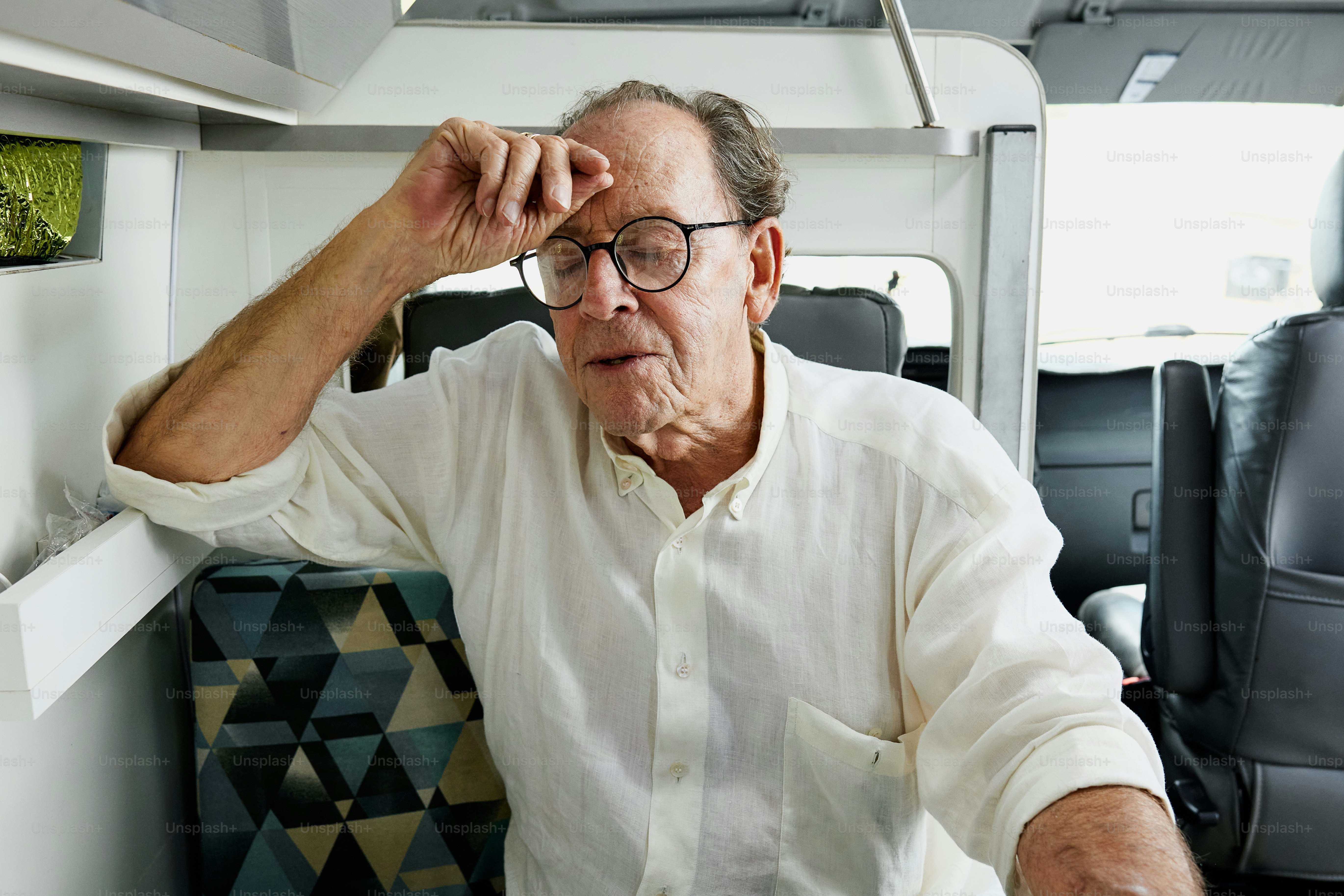 Ein Mann sitzt auf einem Stuhl mit der Hand auf dem Kopf