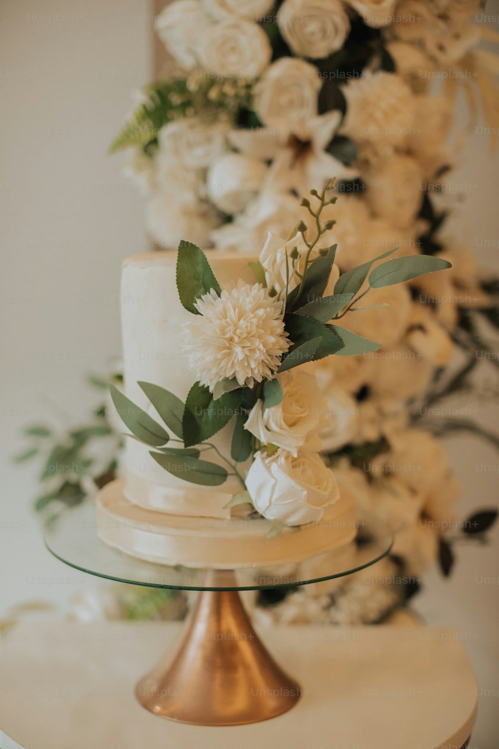 um bolo de casamento com flores brancas e vegetação