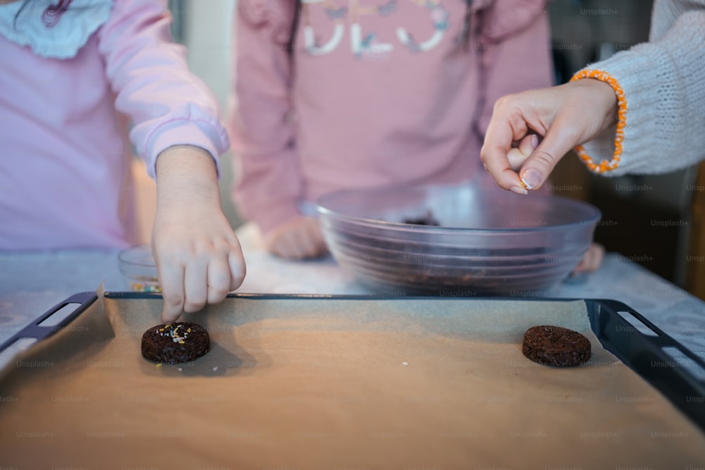 two young girls are making donuts on a table