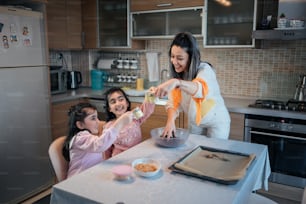 a woman and two girls in a kitchen