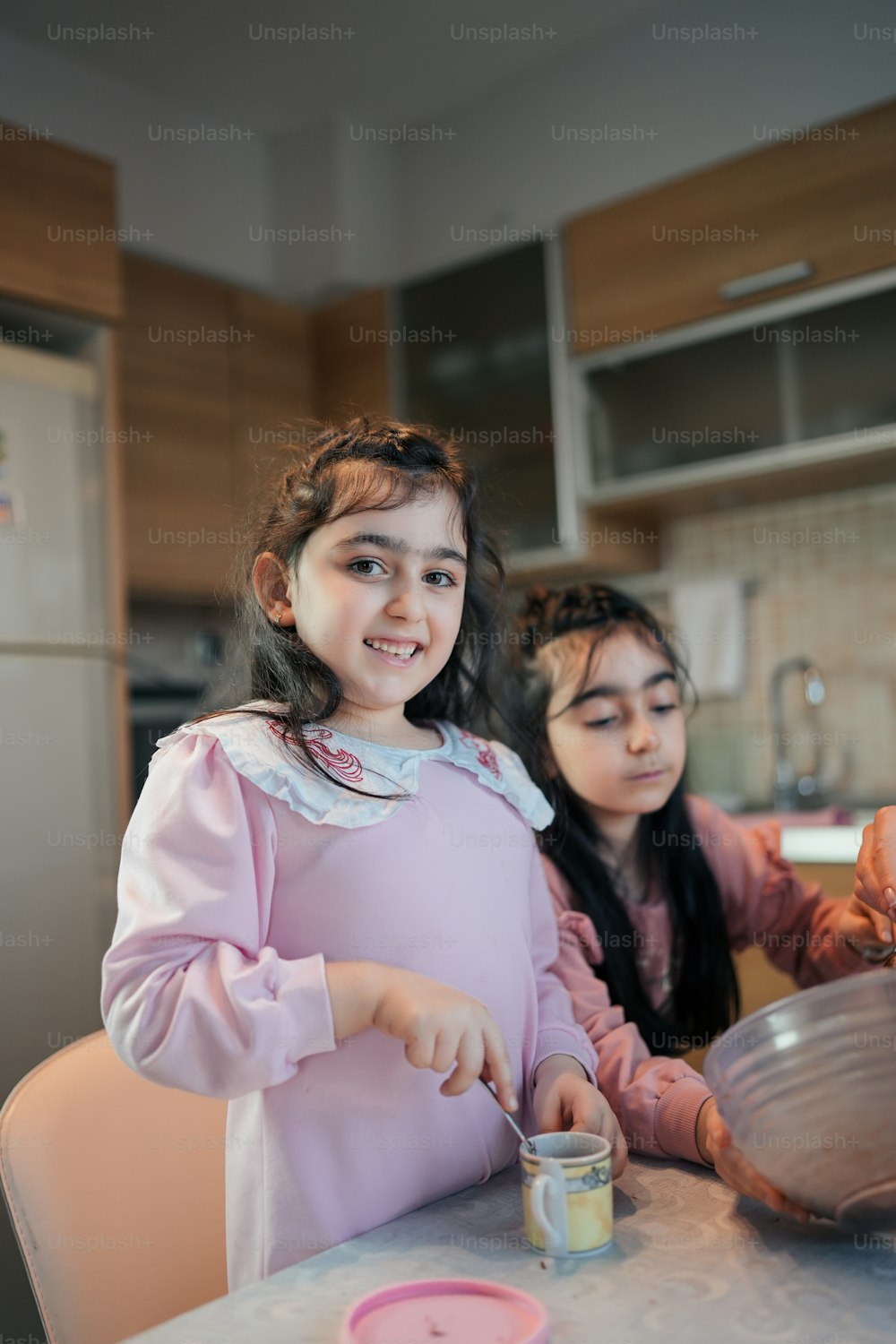 two little girls sitting at a kitchen table