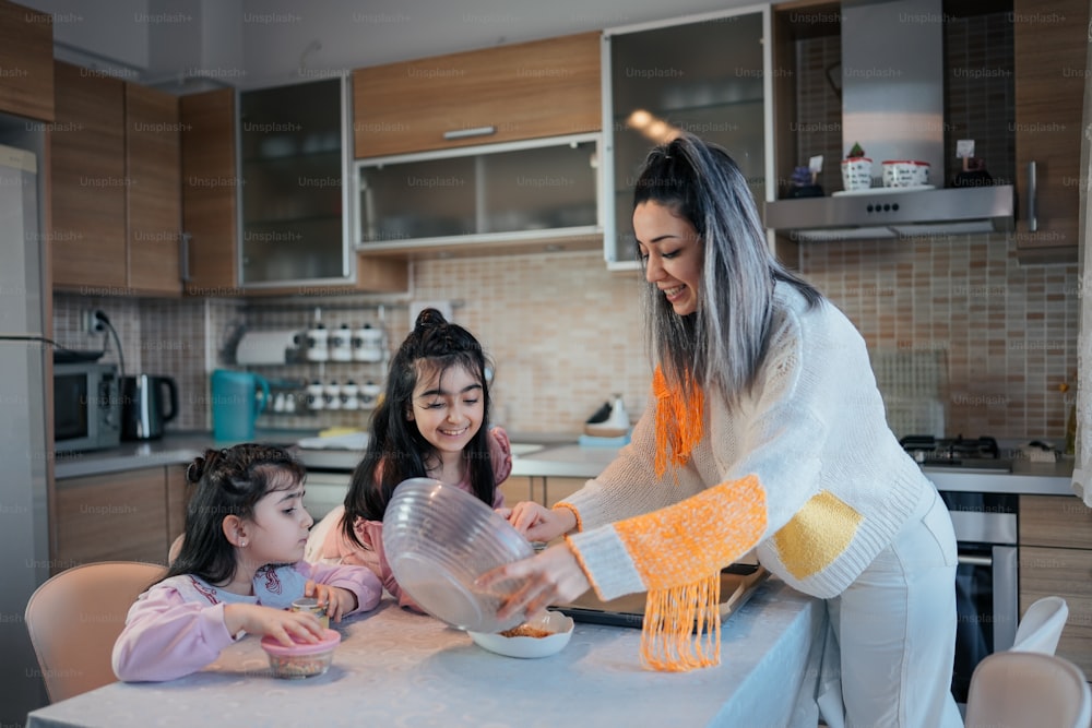 a woman and two young girls are in the kitchen