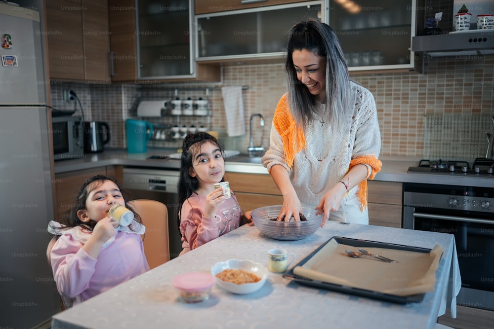 a woman and two young girls in a kitchen