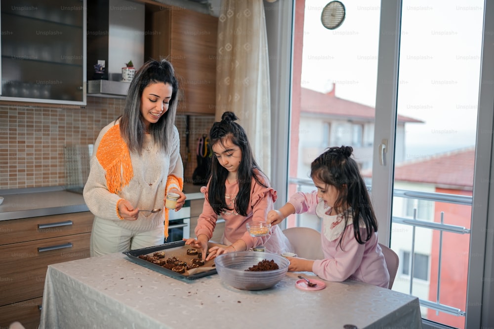 a woman and two young girls making food in a kitchen
