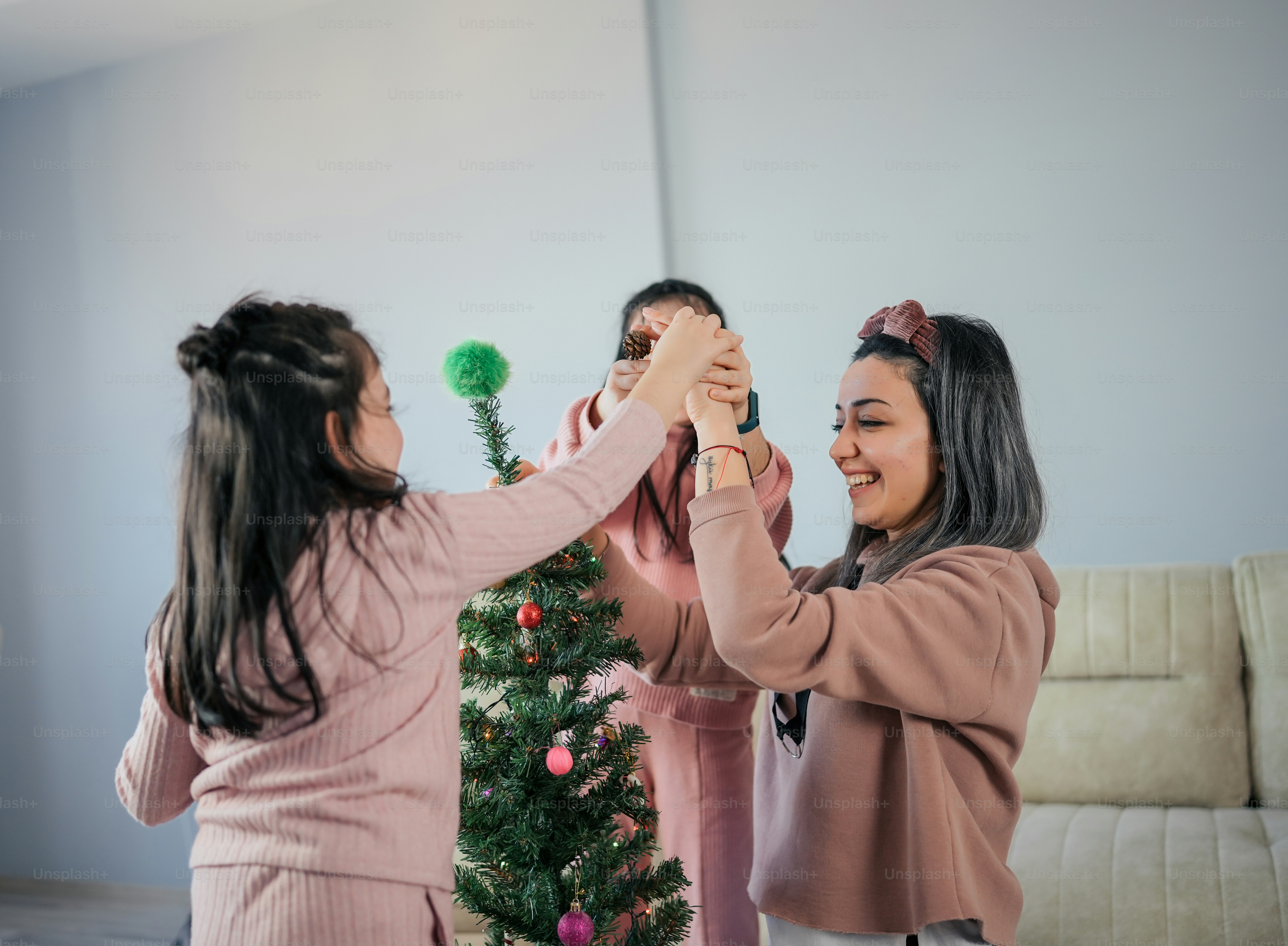 A group of women standing around a christmas tree photo – Christmas ...