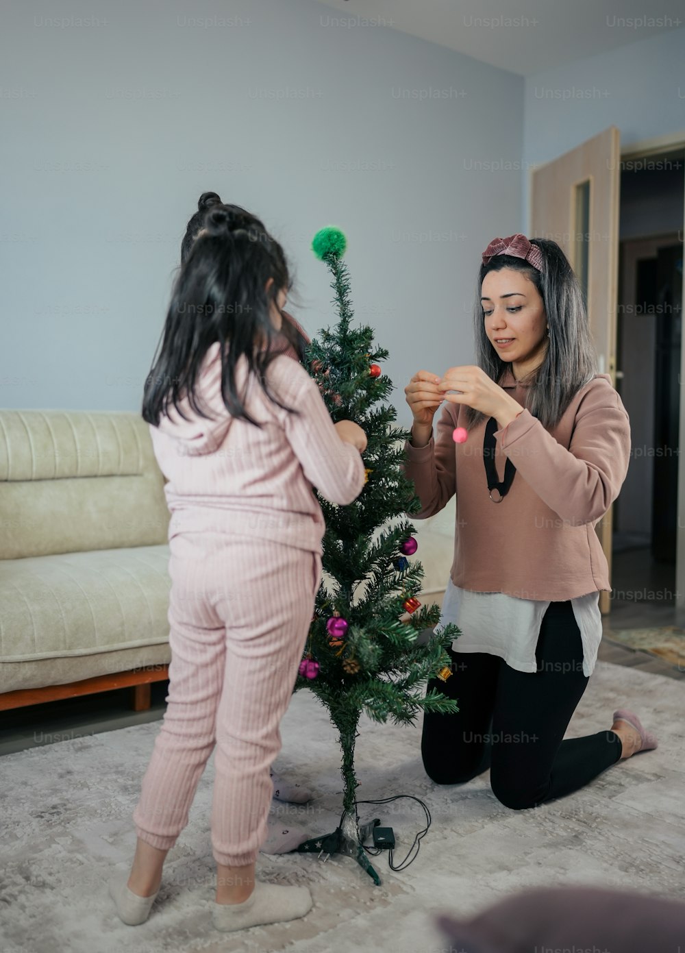 two women decorating a small christmas tree