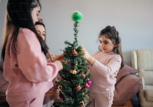 two girls decorating a small christmas tree