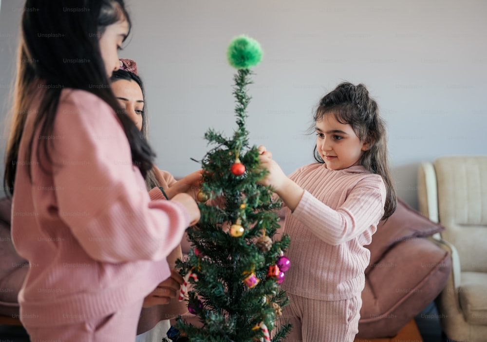 Dos niñas decorando un pequeño árbol de Navidad