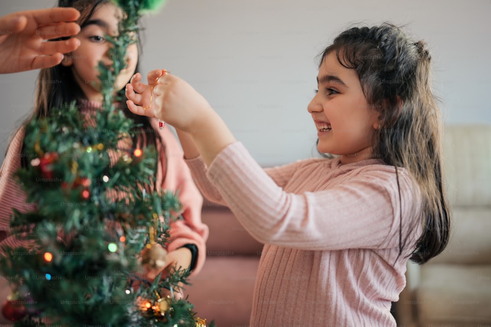 a little girl putting decorations on a christmas tree