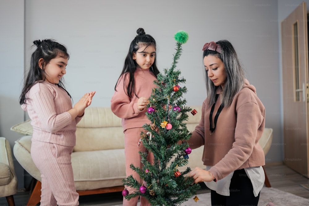 Tres niñas decorando un árbol de Navidad en una sala de estar