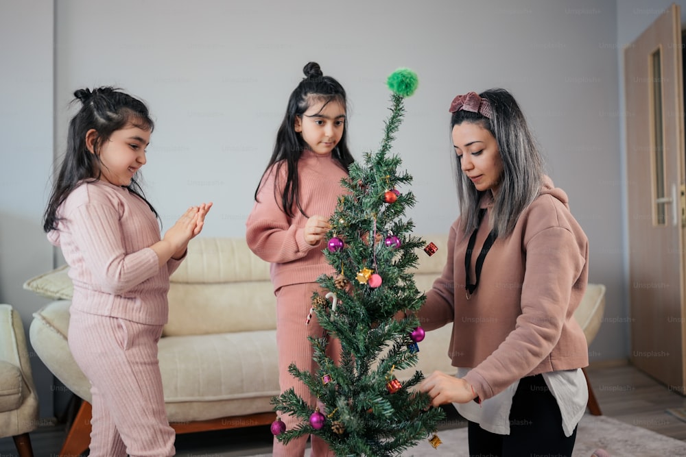 three girls decorating a christmas tree in a living room