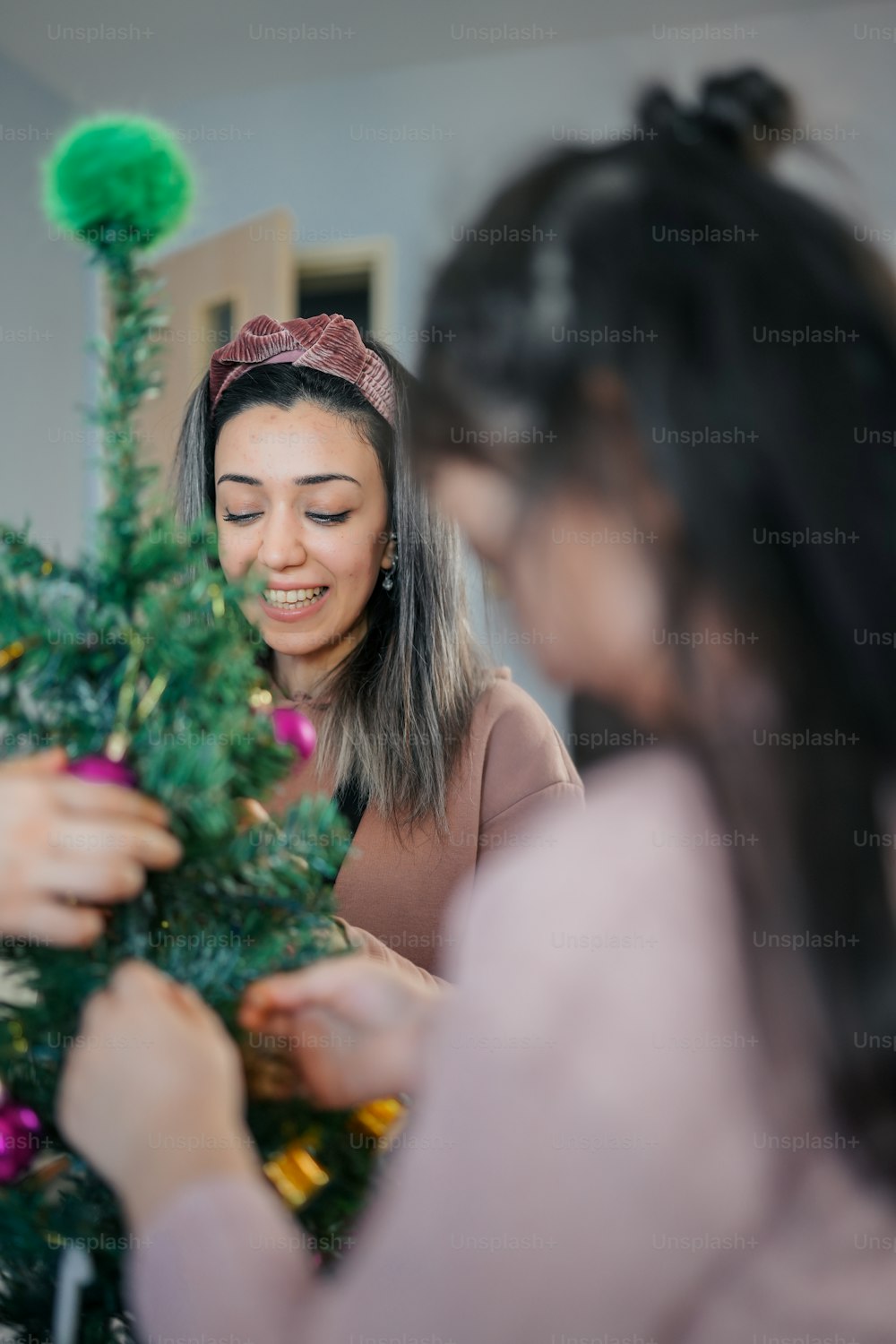 Dos mujeres decorando juntas un árbol de Navidad