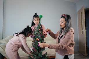 two women decorating a christmas tree in a living room