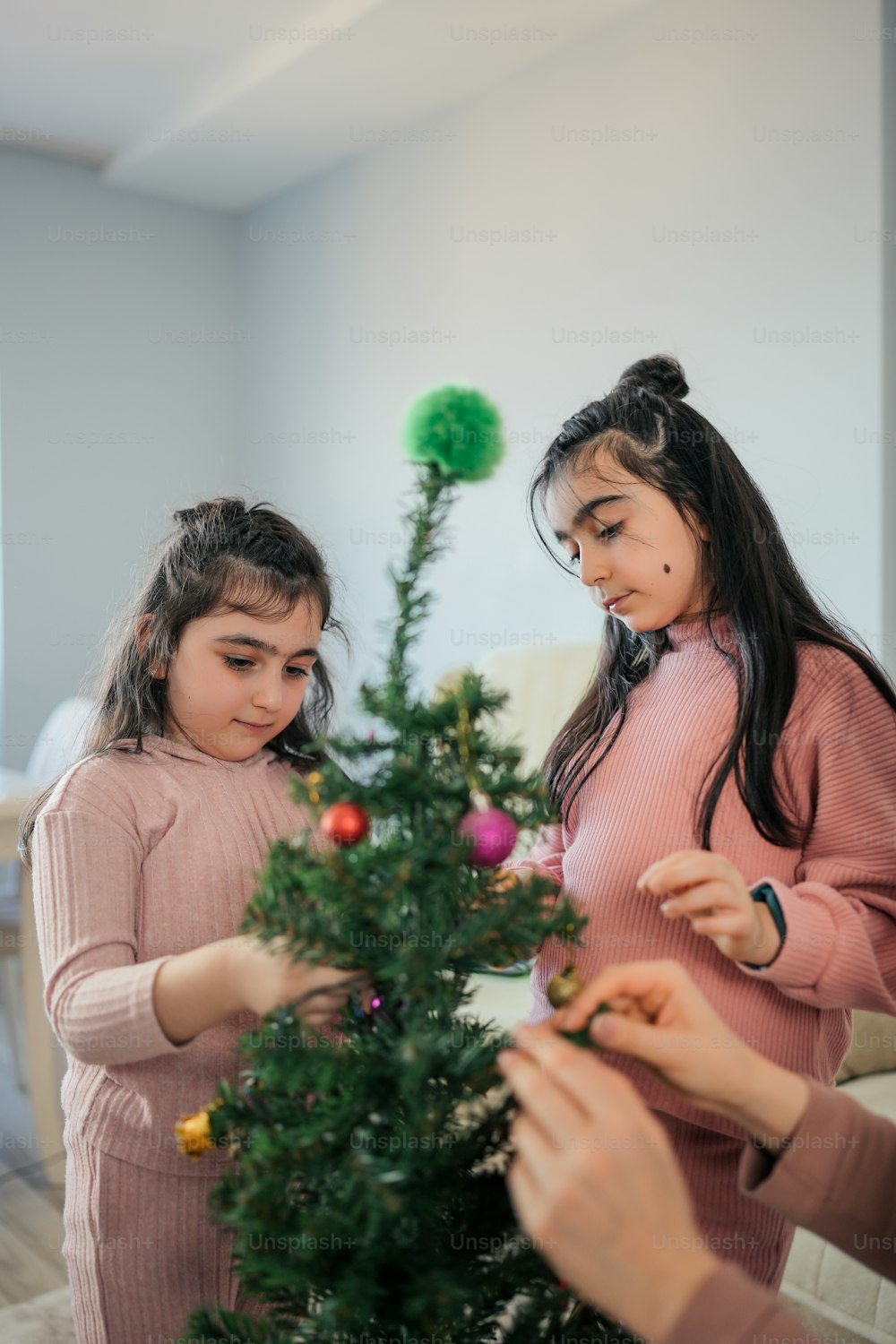 two girls decorating a christmas tree together