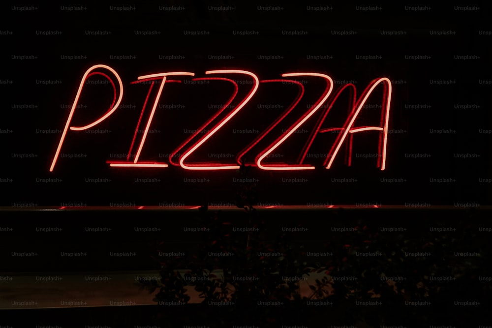 a pizza sign lit up in the dark