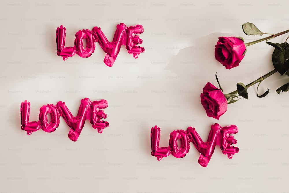 La palabra amor deletreada con globos rosados y flores
