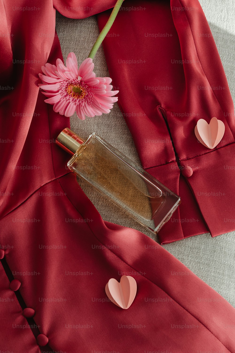 um frasco de perfume ao lado de uma flor rosa