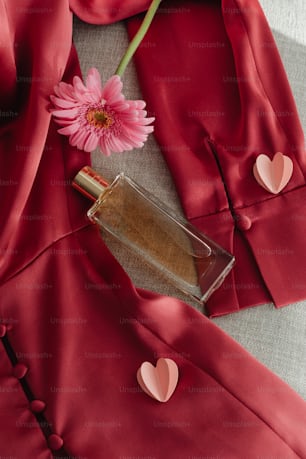 a bottle of perfume next to a pink flower