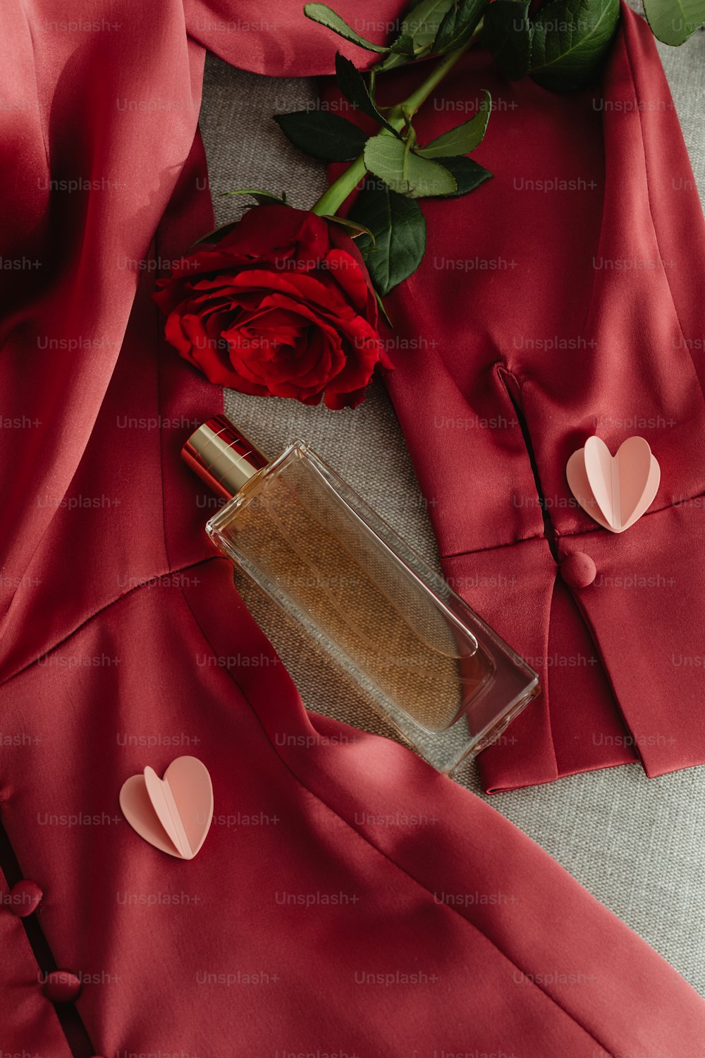 Un frasco de perfume junto a una rosa roja